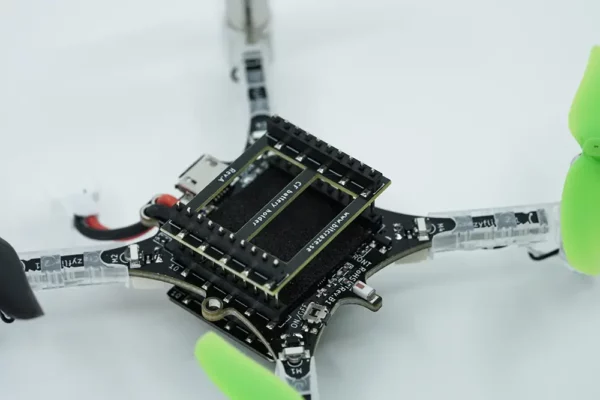 Close-up of a drone's electronic components and green propellers, focusing on the circuit board and wiring