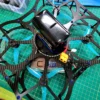 Close-up of a custom-built drone with a carbon fiber frame and blue LED lights, placed on a green cutting mat.