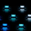 Multiple small drones illuminated with various colored lights, arranged in a grid pattern against a dark background